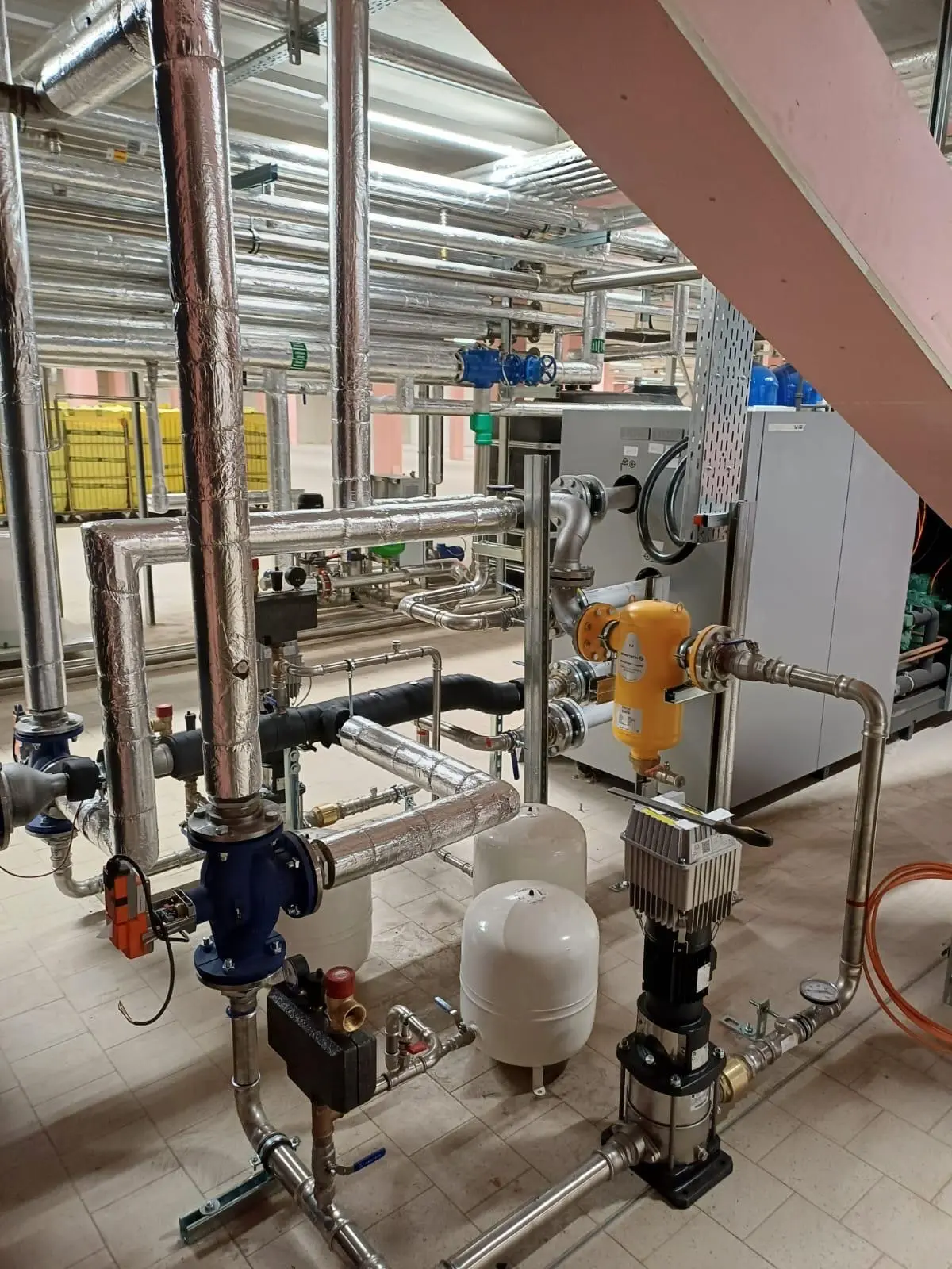 Technikraum mit installierter Industriewärmepumpe und Rohrleitungssystem in einem Wäschereibetrieb